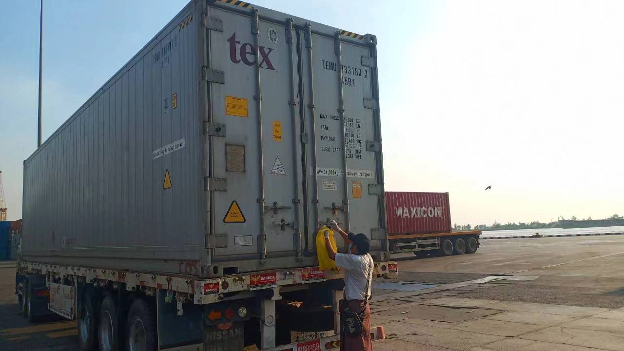 A worker sealing the doors of a shipping container on a trailer