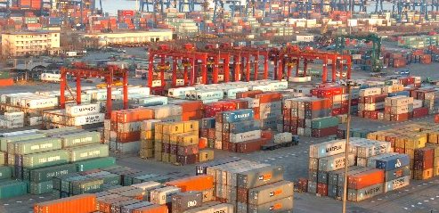 A container terminal with stacked shipping containers and red gantry cranes